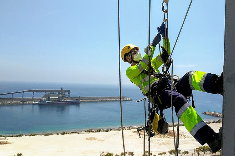 Trabajador inspeccionando un puente colgado de arnés de seguridad