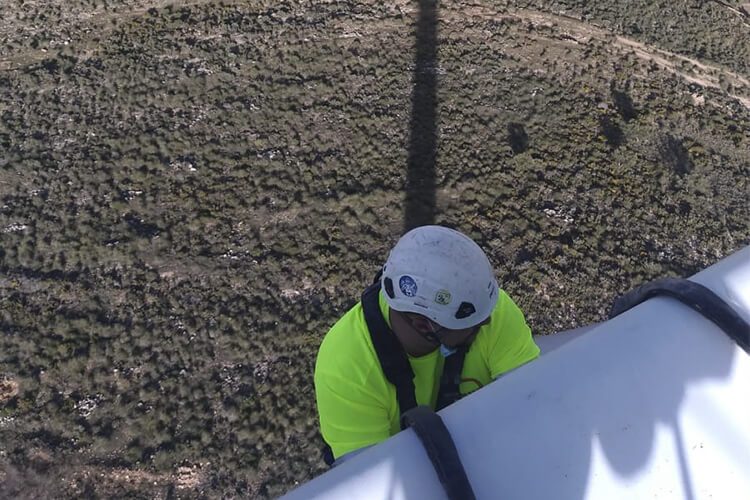 Hombre trabajando a gran altura en una torre eólica